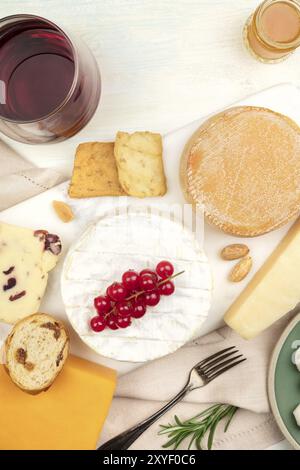 Un assortimento di vari tipi di formaggio con vino, ripresa dall'alto su uno sfondo luminoso con un posto per il testo Foto Stock