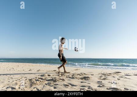 Uomo atletico che calcia la spiaggia Foto Stock