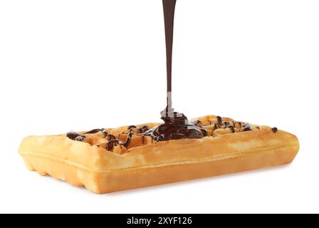 Versare del delizioso cioccolato fuso sul waffle isolato sul bianco Foto Stock