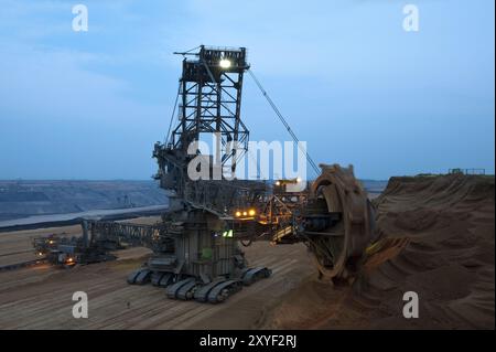 Escavatore gommato a benna escavatore gommato in una miniera a cielo aperto nelle ore blu Foto Stock