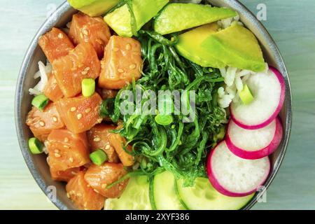 Invio di un poke di salmone con avocado, wakame e cetrioli, overhead close-up shot Foto Stock