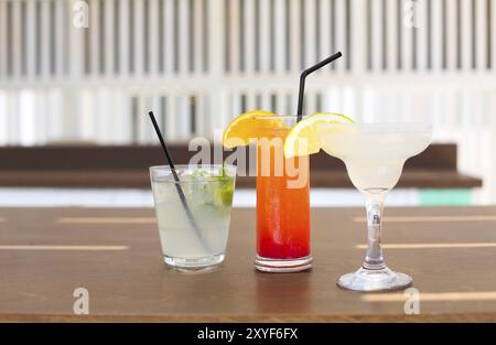 Bicchieri da cocktail su sfondo di legno. Margarita, tequila sunrise, mojito Foto Stock