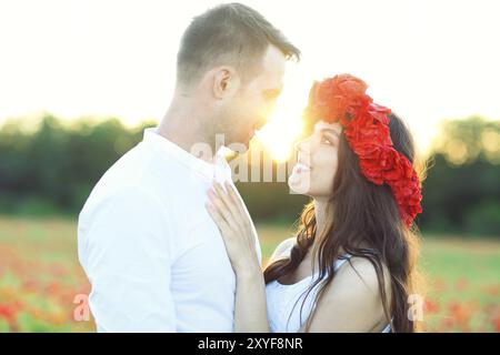 Giovane coppia felice in amore che bacia e abbraccia al campo del papavero Foto Stock