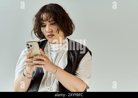 Una donna con un giubbotto vivace guarda con attenzione il suo telefono. Foto Stock