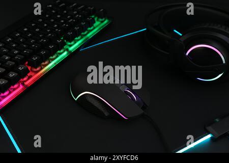 Mouse per computer, tastiera RGB e cuffia su sfondo nero, primo piano Foto Stock