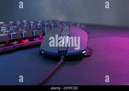 Mouse per computer e tastiera RGB con luci al neon su sfondo scuro, primo piano Foto Stock