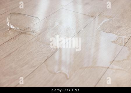 Bicchiere con bibita versata su pavimento in legno, primo piano Foto Stock