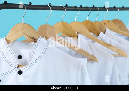 Diversi cappotti dello chef su un appendiabiti su sfondo azzurro, primo piano Foto Stock