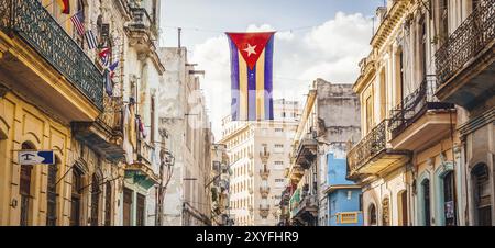 Una bandiera cubana con i buchi che si infrangono su una strada nel centro dell'Avana. La Habana, come la chiamano la gente del posto, è la capitale di Cuba Foto Stock