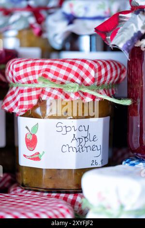 Regno Unito. Chutney di mele speziate fatte in casa conservate in vasetti di vetro, etichettate e rifinite con un topper in tessuto. prodotto con mele da cucina stagionali coltivate in casa Foto Stock