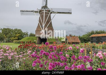 Mulino a vento olandese circondato da fiori colorati in un giardino in una giornata nuvolosa, Eibergen, Gheldria, Paesi Bassi Foto Stock