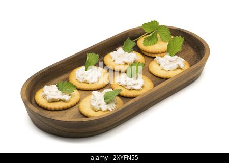 Cracker con insalata di tonno in un vassoio di legno su sfondo bianco Foto Stock