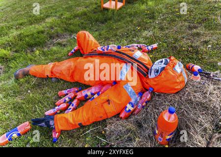 DJUPIVOGUR, ISLANDA, 21 GIUGNO: Manichino maschile giace sull'erba ricoperto di bottiglie di succo d'arancia il 21 giugno 2013 a Djupivogur, Islanda, Europa Foto Stock