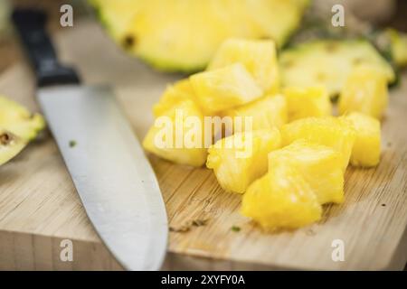 L'ananas tagliato a fette su un vecchio tavolo di legno come primo piano dettagliato, messa a fuoco selettiva Foto Stock