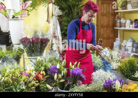 Fiorista donna felice, che fa accordi e sorride alla telecamera. Proprietario di un negozio di fiori per piccole imprese Foto Stock