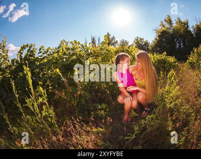 Felice sua madre e la sua piccola figlia nel tempo del raccolto nella vigna Foto Stock