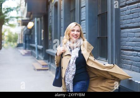 Una donna di mezza età attraversa la città e sorride. Concetto di felicità Foto Stock