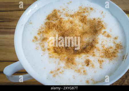 Delizioso cappuccino fatto in casa, in una tazza bianca, su un tavolo di legno. Caffè fatto in casa. Foto Stock