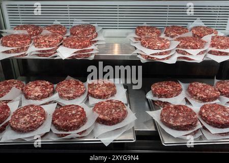 Polpettine di hamburger preparate al momento in vendita in una macelleria. Foto Stock