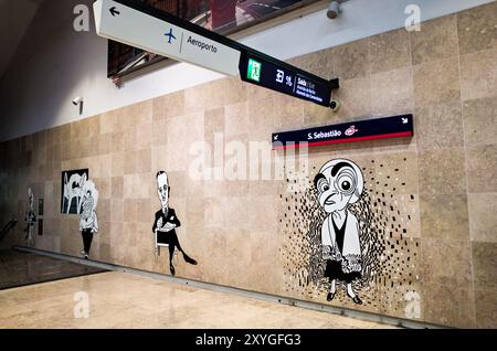 LISBONA, Portogallo: La stazione della metropolitana dell'aeroporto Humberto Delgado di Lisbona, con i pittoreschi murales dei cartoni animati del famoso fumettista portoghese António Antunes. L'opera d'arte raffigura caricature di varie figure pubbliche e celebrità portoghesi, aggiungendo un tocco culturale unico al centro di trasporto sotterraneo dell'aeroporto. Foto Stock