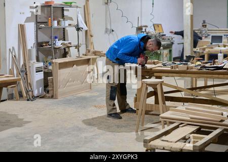 Primo piano del lavoratore tagliando e planando con cura pezzi di legno per mobili nell'industria del legno Foto Stock