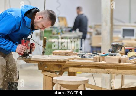 Primo piano del lavoratore tagliando e planando con cura pezzi di legno per mobili nell'industria del legno Foto Stock