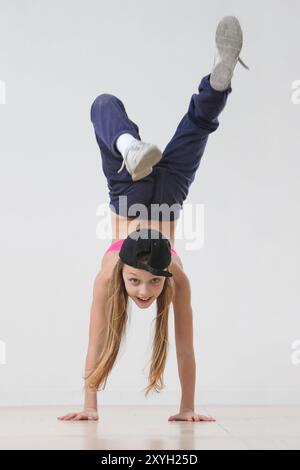 allegra ballerina hip hop preadolescente che fa handstand su sfondo grigio Foto Stock