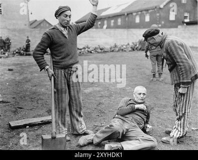 In questa foto violenta, due prigionieri liberati si preparano a battere una guardia che è sul pavimento. In background le truppe statunitensi stanno sommariamente giustiziando altre 30 guardie circa. Ci sono stati 32000 morti documentate lì e molte altre migliaia non documentate. Il campo principale (Dachau aveva 100 sottocampi) fu liberato dall'esercito americano il 29 aprile 1945. Foto Stock