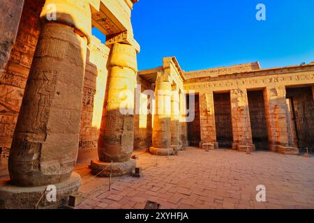 Imponenti colonnati con rilievi nella prima corte all'interno del magnifico Tempio di Medinet Habu - Tempio Mortuario di Ramses III costruito intorno al 1170 a.C. a Luxor, in Egitto Foto Stock