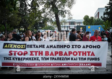 Atene, Grecia. 29 agosto 2024. I manifestanti tengono uno striscione che recita "Stop crudeltà del governo delle banche e dei fondi" durante una protesta contro uno sfratto familiare dalla loro casa a causa di pignoramenti immobiliari. I manifestanti incolpano le banche i fondi e il governo greco per crudeltà, mentre affermano che la famiglia che non può rimborsare il loro mutuo ha un figlio disabile. Il paese si trova di fronte a un peggioramento della carenza di alloggi che è diventato un grave problema sociale, rendendolo estremamente inaccessibile per le famiglie comuni. Crediti: Dimitris Aspiotis/Alamy Live News Foto Stock