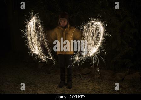 Un bambino dipinge cerchi di luce con scintillanti Foto Stock