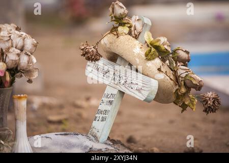 Corona funebre a base di rose secche o di seta e ghirlanda di polistirene su una piccola croce di legno Foto Stock