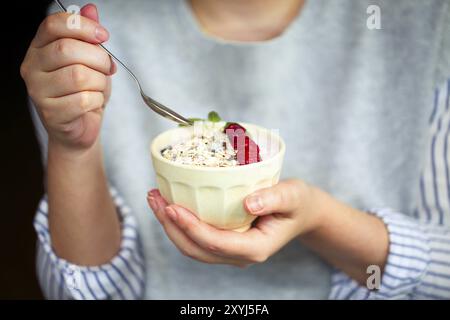Sana colazione yogurt greco, granola e lamponi nella ciotola in mani di donna Foto Stock