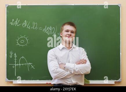 Studente ragazzo in piedi vicino alla lavagna in aula Foto Stock