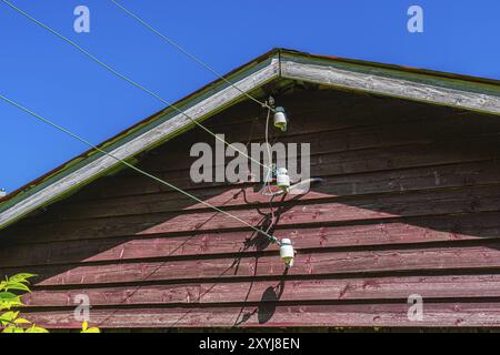 Vecchie linee elettriche che si collegano al lato di una vecchia casa in legno Foto Stock