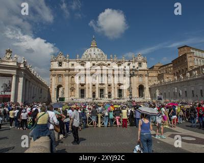 Basilica di San Pietro con una grande folla nella piazza di fronte ad essa sotto un cielo azzurro, roma, italia Foto Stock