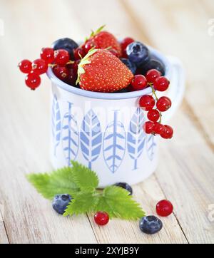 Deliziosa frutta fresca nella tazza bianca e blu sul tavolo Foto Stock