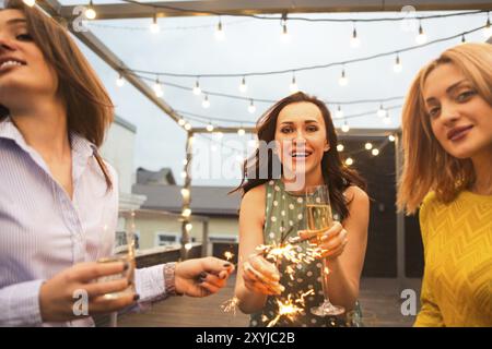 Un gruppo di ragazze che partying con flauti con vino frizzante e il Bengala fire divertirsi sulla parte Foto Stock