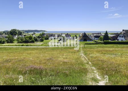 Vista di un villaggio costiero con case sul tetto di paglia circondate da campi in una giornata di sole, Ruegen (Gross Zicker) Foto Stock