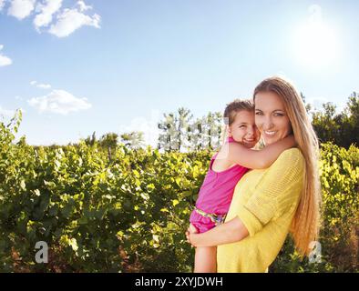 Felice sua madre e la sua piccola figlia nel tempo del raccolto nella vigna Foto Stock