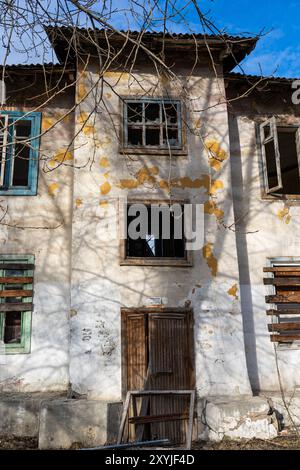 Una vecchia casa abbandonata a due piani con finestre e porte a bordo Foto Stock