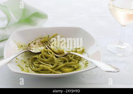 Primo piano della mangiato linguine con pesto genovese, patate e vino bianco vetro Foto Stock