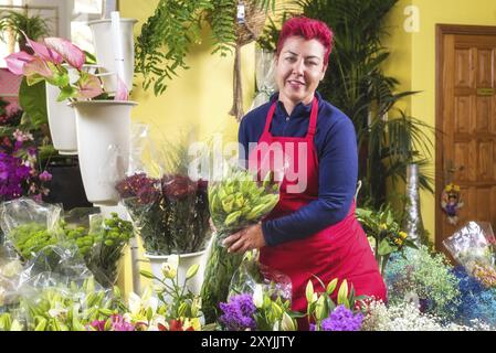 Fiorista donna felice, che fa accordi e sorride alla telecamera. Proprietario di un negozio di fiori per piccole imprese Foto Stock