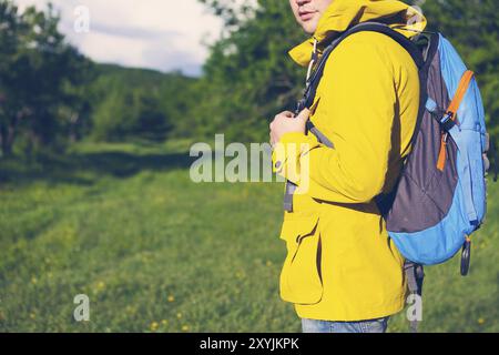 Vista laterale del giovane uomo con zaino trekking nella foresta Foto Stock