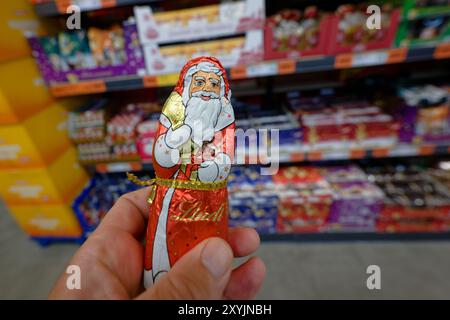 Grevenbroich, Germania. 30 agosto 2024. ILLUSTRAZIONE - i baccalà al cioccolato e altri dolci natalizi si trovano su uno scaffale di un supermercato norma. Una mano tiene davanti un Lindt Babbo Natale. Gingerbread e biscotti sono già in vendita in molti negozi. Un sondaggio dimostra che alla maggior parte dei consumatori non piace. (Alla dpa "maggioranza contro la vendita anticipata di speculoos e pan di zenzero") credito: Henning Kaiser/dpa/Alamy Live News Foto Stock