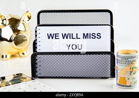 CI MANCHERAI scritto su un quaderno in uno stand su sfondo bianco Foto Stock