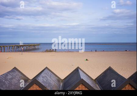 La spiaggia sabbiosa di Lowestoft nel Suffolk con capanne in primo piano Foto Stock