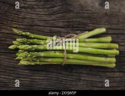 Mazzetto di freschi Asparagi verdi spears legati con spago su una tavola in legno rustico Foto Stock