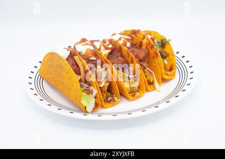 tacos messicani di pollo grattugiato e a pezzi con pomodoro, lattuga, cavolo, ingredienti a base di panna acida e nacho al gusto di gusci duri. Isolato su un whi Foto Stock