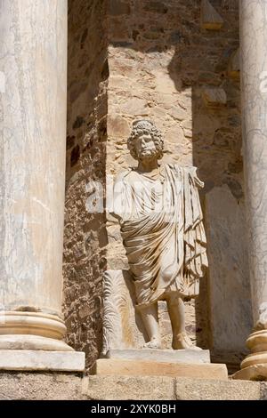 Statua in pietra di fronte a antiche colonne e muri in pietra, un dettaglio dell'architettura romana e dei siti storici, il Teatro Romano de Merida, il teatro romano Foto Stock